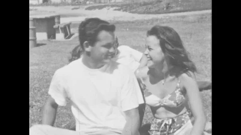 1960s: Young man and woman at picnic. Couple stand up and walk toward car, Stock Footage