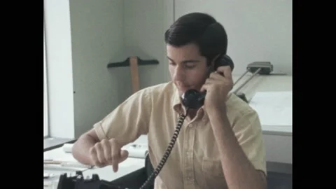 1960s: Young man sits at drafting table, picks up telephone, makes phone call, Stock Footage 194489530