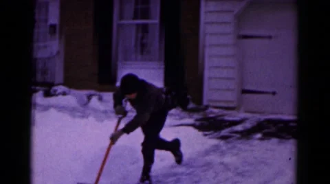 1961: boy playfully shovels snow from driveway during winter HAGERSTOWN Stock Footage