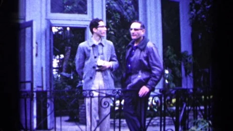 1961: A Man Hiding Something on His Back While Talking to Another Man Video stock 73343837