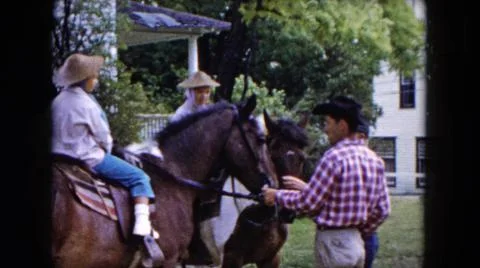 1961:BUFFALO NEW YORK USA.Two Children In Hats Riding Horses In A Yard While Men Stock Photos