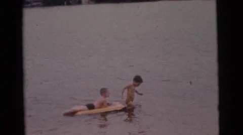 1963: a boy on a raft in the water being pulled by another child CAMDEN Stock Footage