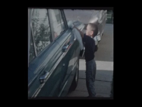 1963 Little boy dries vintage antique car after washing it Stock Footage
