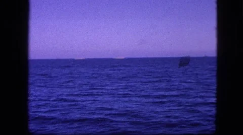 1963: view of the ocean waves from moving boat with mountains Stock Footage