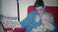 1964: Dad Showing Child Box Of Chocolates In Comfortable Morning Robe Fashion. Stock Footage