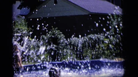 1964: a little girl splashes into an above ground pool in a backyard. CAMDEN Stock Footage