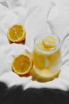 A closeup of a lemon juice with lemons on the bed xkwx bed, closeup, lemon, juice, fruit, glass, fresh, food, drink, citrus, cocktail, healthy, yellow, background, sweet, summer, slice, beverage, white, cold, tropical, vitamin, organic, diet
