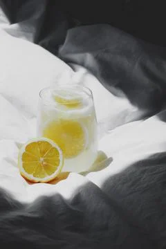 A closeup of a lemon juice with lemons on the bed xkwx bed, closeup, lemon, juice, fruit, glass, fresh, food, drink, citrus, cocktail, healthy, yellow, background, sweet, summer, slice, beverage, white, cold, tropical, vitamin, organic, diet