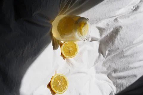 A closeup of a lemon juice with lemons on the bed xkwx bed, closeup, lemon, juice, fruit, glass, fresh, food, drink, citrus, cocktail, healthy, yellow, background, sweet, summer, slice, beverage, white, cold, tropical, vitamin, organic, diet