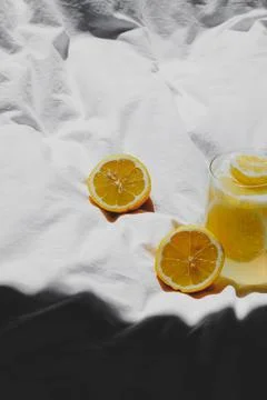 A closeup of a lemon juice with lemons on the bed xkwx bed, closeup, lemon, juice, fruit, glass, fresh, food, drink, citrus, cocktail, healthy, yellow, background, sweet, summer, slice, beverage, white, cold, tropical, vitamin, organic, diet