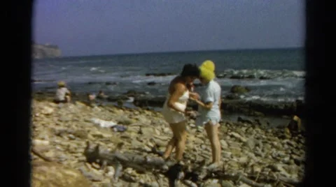 1966: family in swimsuits and funny hats at rocky beach area CALIFORNIA Stock Footage