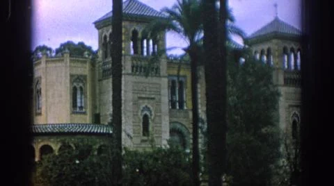 1966:SPAIN. Large Brown Building Multiple Towers With Palm Trees And Man In Blue Fotos de archivo