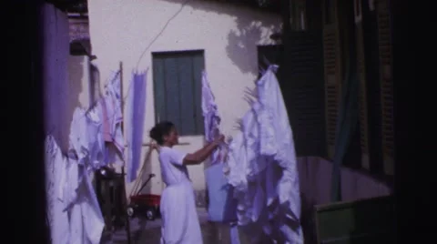 1967: african american women doing laundry outside clothesline hanging sheets Stock Footage