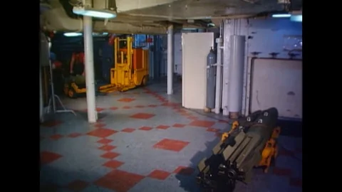 1967 - Below deck on the USS Constellation, US Navy seamen wheel bombs onto an Stock Footage 106294964
