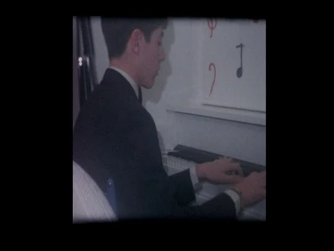 1967 Boy plays old upright piano for friends Vídeo Stock 72395815