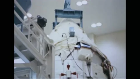 1967 - A NASA engineer helps guide a command service module from a work stand Stockbeeldmateriaal 232848193