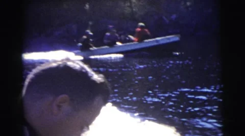 1967: two boats diverge while traveling on a tree-lined rippling river at Stock Footage