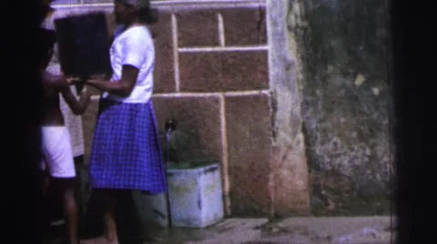 1967: woman is helping to little boy to put gallon of water on top of his head Stock Footage
