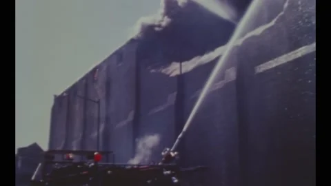 1968 - Firefighters use hoses and ladders in their battle against a raging Stock Footage 246304736