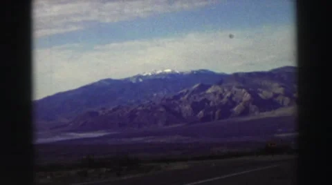 1969: a man standing near a vehicle with a beautiful mountain in the background Stock Footage