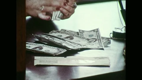 1970s :  After a teller counts a man's money, he gives it back to her to be Stock Footage