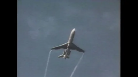 1970s: Airplane flies and leaves smoke trails behind. Airplane wing in the air. Stock Footage