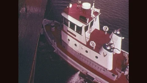 1970s: Boat and its back deck, wake on water. Worker tosses rope over side of Stock Footage