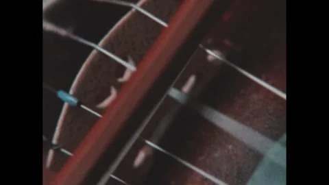 1970s: Bow is pulled over strings of violin. Woman plays violin. People making Stockbeeldmateriaal 295297006