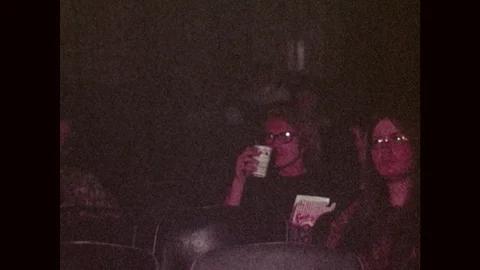 1970s: Boy eats and drinks in movie theatre seat. Boy eats popcorn and watches 스톡 동영상 103323610