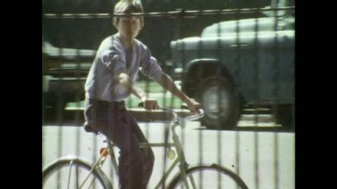 1970s: Boy rides bicycle. Boys play basketball on basketball court outside. Boy Stock Footage