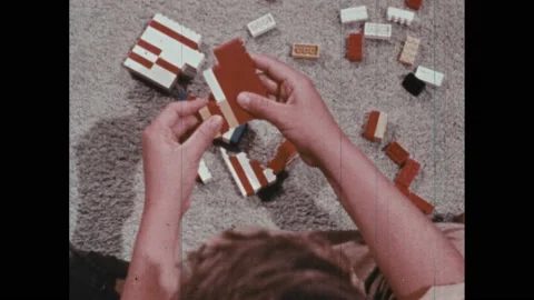 1970s: Boy sits on floor, stacks Lego bricks. Girl twists pigtail braids. Stock Footage 239264967