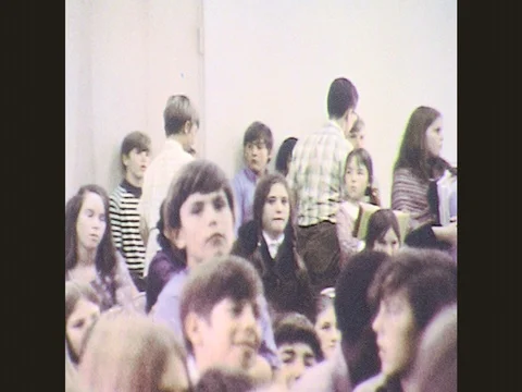 1970s: Boys and girls leave audience. Boy laughs. Girl holds pencil and listens. Stock Footage