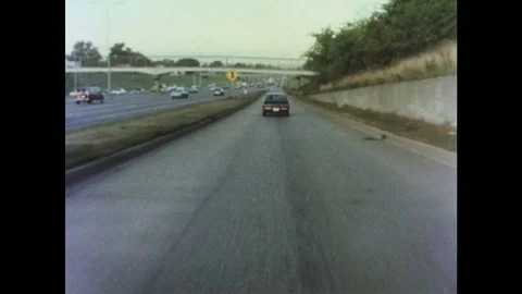 1970s: Car drives on entry lane to highway. Car turns on left directional Stock Footage