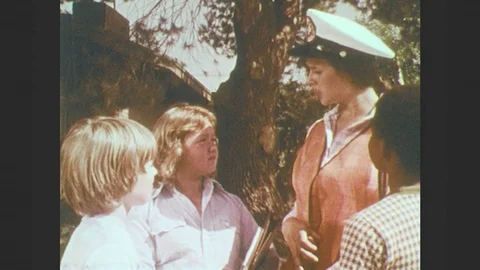 1970s: Children talk to crossing guard. Crossing guard smiles and talks. Stock Footage