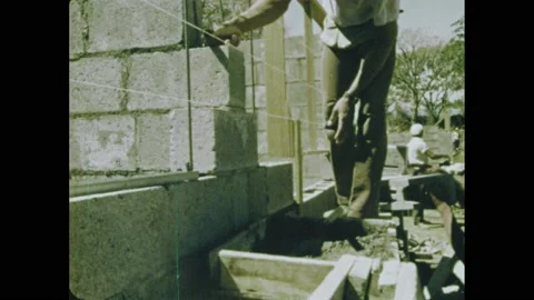 1970s: Construction worker laying cinder blocks over rebar. Worker hammering Video stock 164544365
