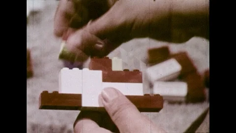 1970s: Dissolve to close up, hands stack Lego pieces / Dissolve to high angle Stock Footage 74440407