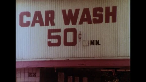 1970s - External shot of do it yourself carwash. Woman washing car. Two teenage Stock Footage 74681336