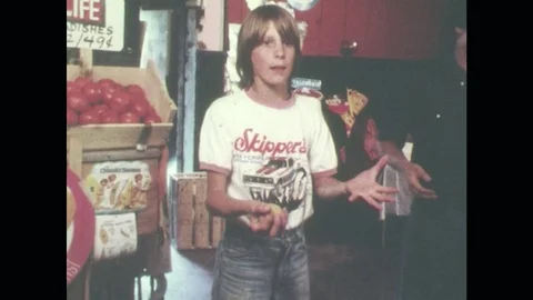 1970s: Farmers market, man teaches juggling, points, throws ball from one hand Stock Footage