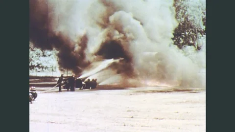 1970s: Firefighters train hoses on large horizontal cylindrical fuel storage Stock Footage