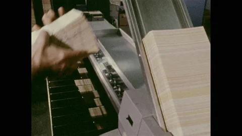 1970s: Forms in document processor. Forms process through large machine. Person Stock Footage 157935485