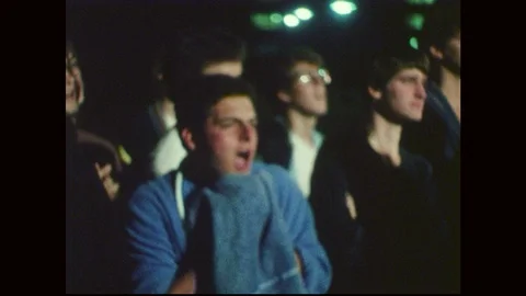 1970s: A group of students stands outside at night, a man holds a towel against Stock Footage 90810306