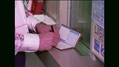 1970s: hands write in checkbook, slide check into slot at counter, grab money Stock-Footage 90809422