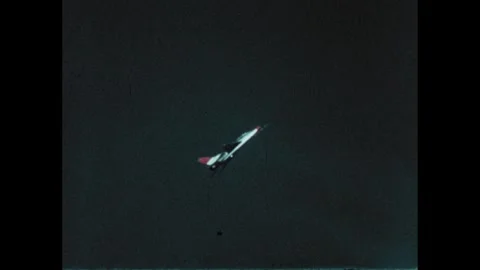 1970s: Jet flies into sky. Rocket engines ignite on launch pad. Hand waves near Stock Footage 270368800