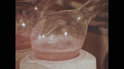 1970s: Liquid bubbles in beaker. Lab workers conduct research. Canned goods on Video stock 135841136