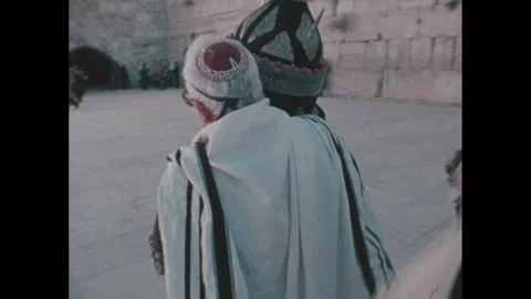 1970s: Man carries the Torah scroll followed by men in prayer shawls. Man walks Stock Footage 279490693