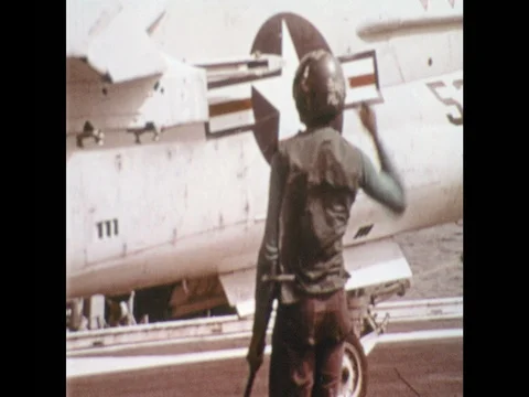 1970s: Man on deck of aircraft carrier. Man in plane, Man on radio. Men cook on Stock Footage