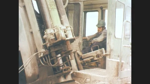 1970s: Man in hard hat inside heavy machinery.  Hand places shell in hole in the 스톡 동영상 78012731