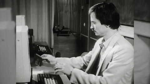 1970s Man Inserts Disc Into Personal Computer Programer Vintage Old Film Movie Stock Footage 87299706