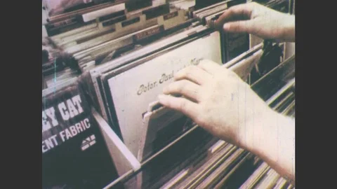 1970s: Man sits on bench, smokes cigarette. Man looks through vinyl records in Stock Footage