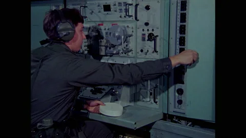 1970s: Man sits at computer control panel.  Lights go off.  Man turns knob.  Man 動画素材 159168228